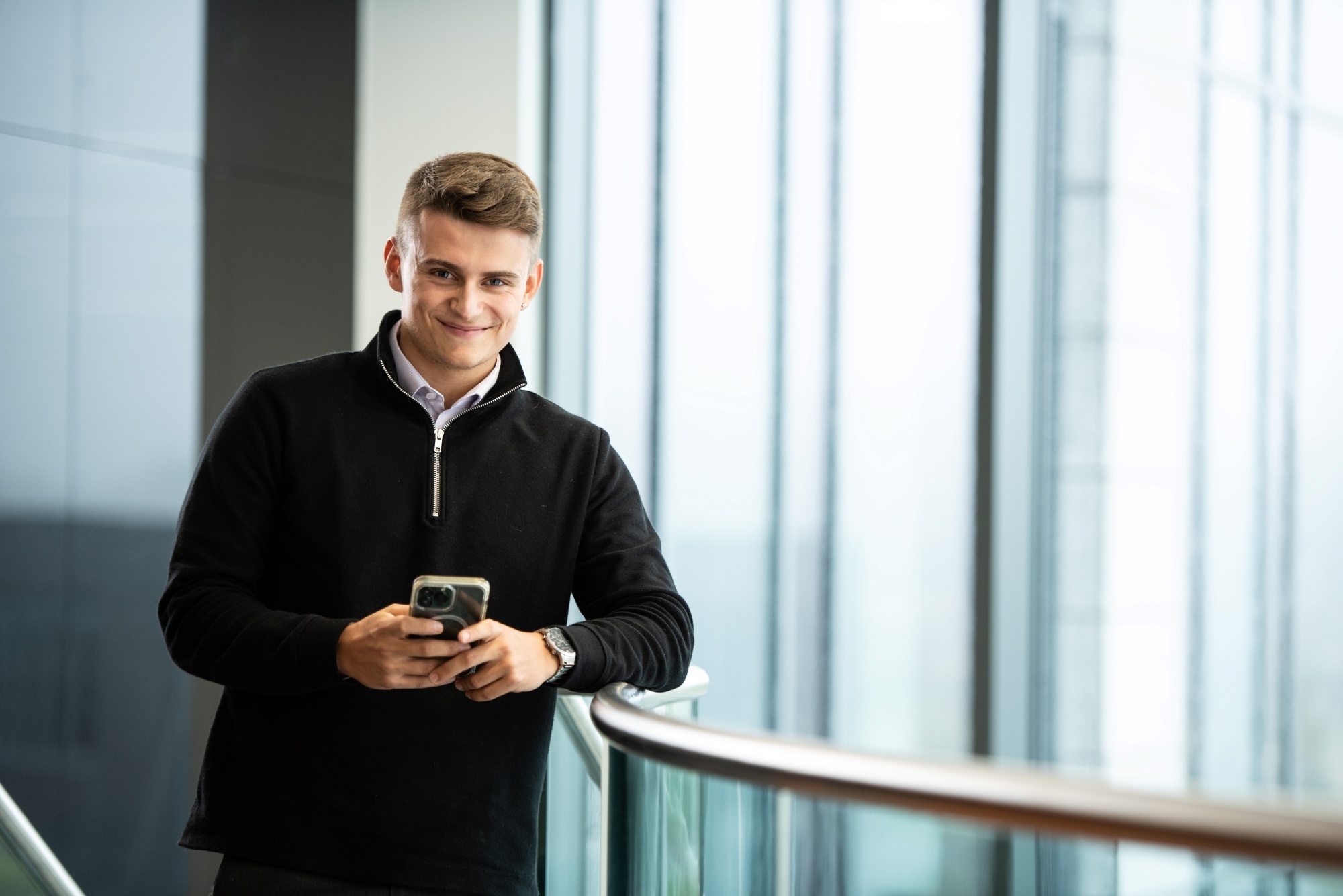 An image of an AAB team member standing in the office on his phone and smiling at the camera.