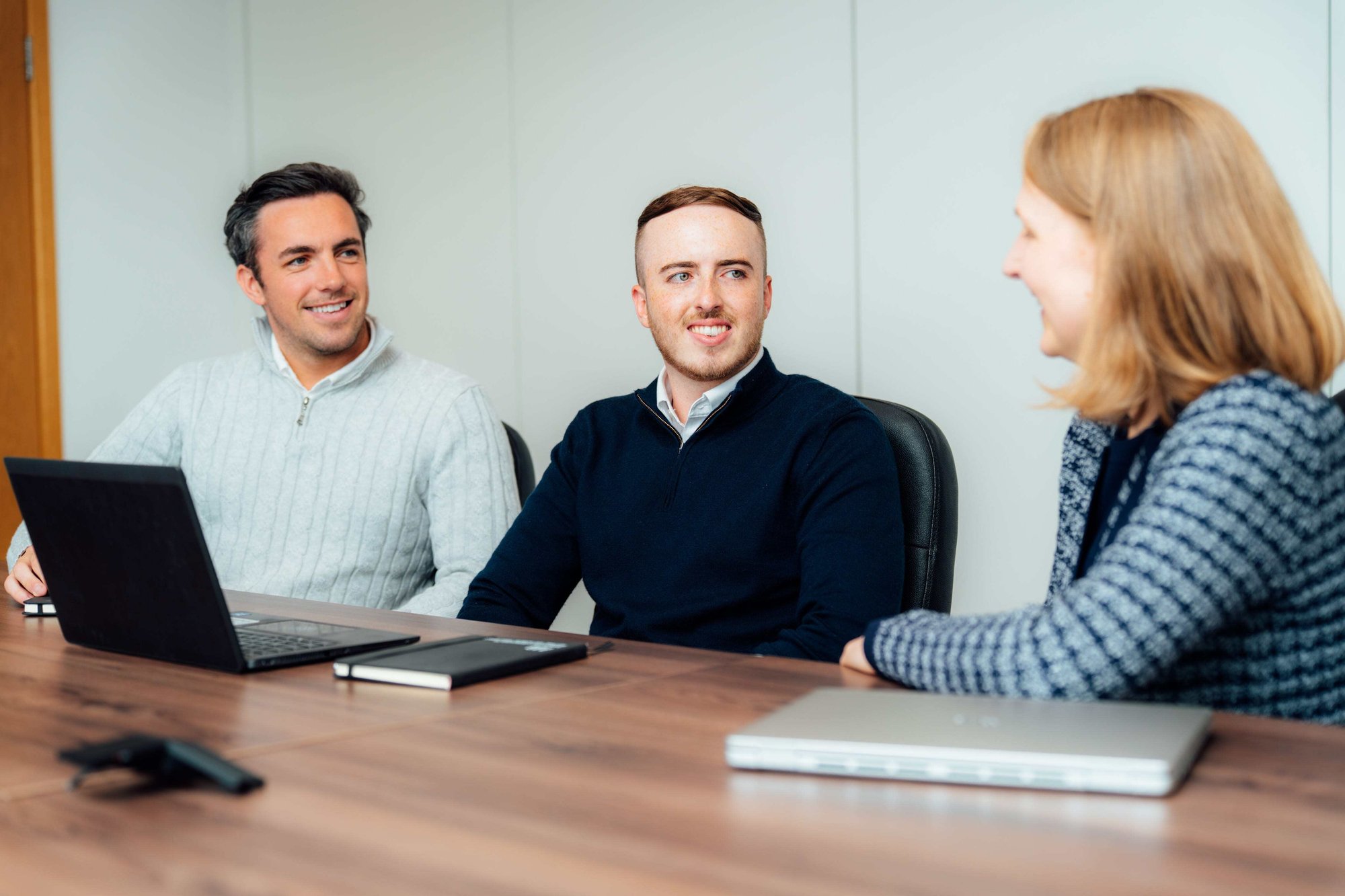 An image of three AAB employees sitting at a desk and sharing conversation.