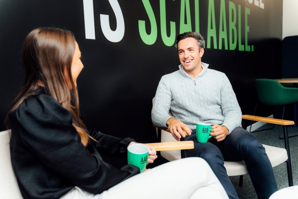 An image of Daniel Lightbody and Lori Young sitting in the AAB office and chatting.