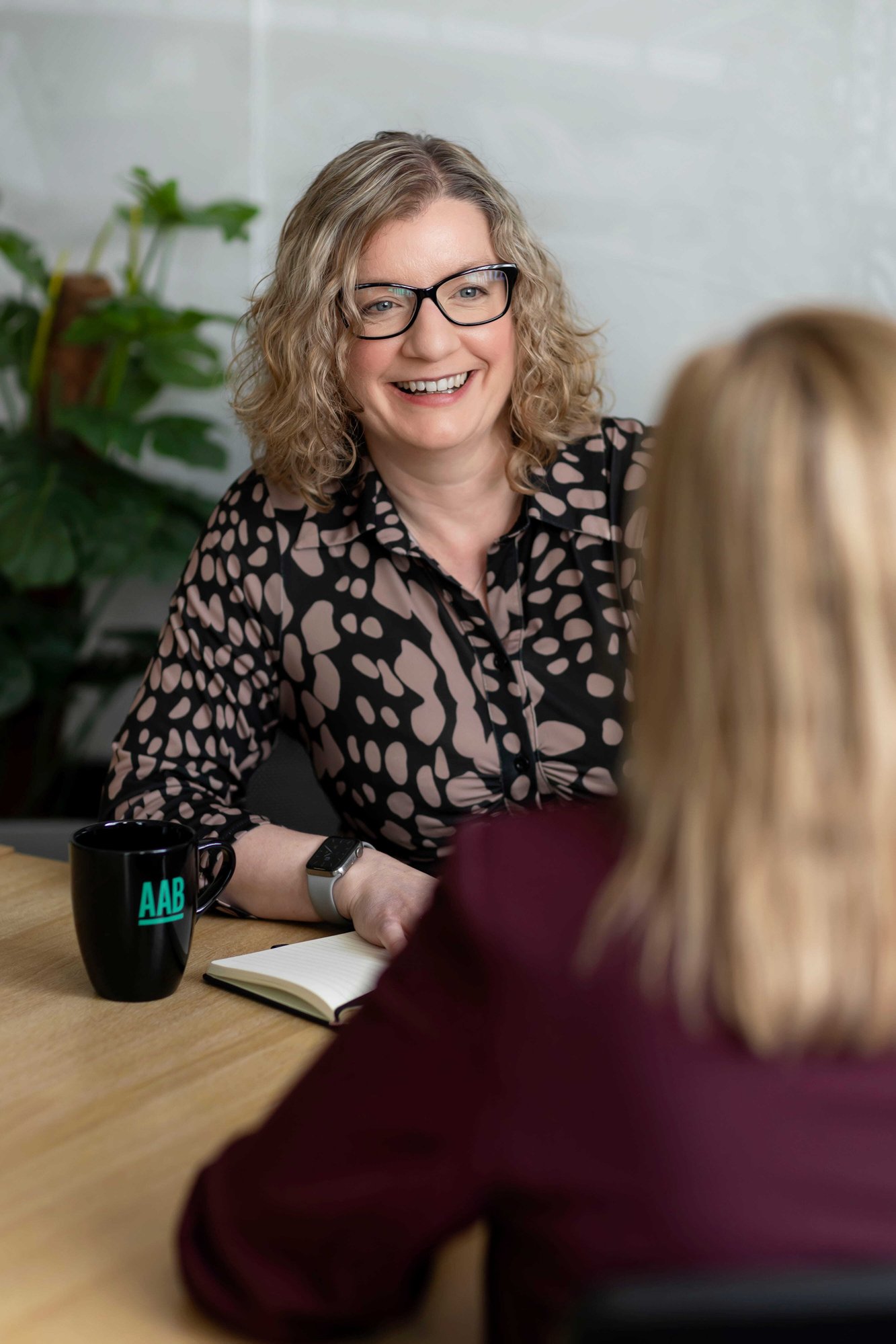 An image of Emma Woods, Jo Waddicker sitting at a desk and smiling.
