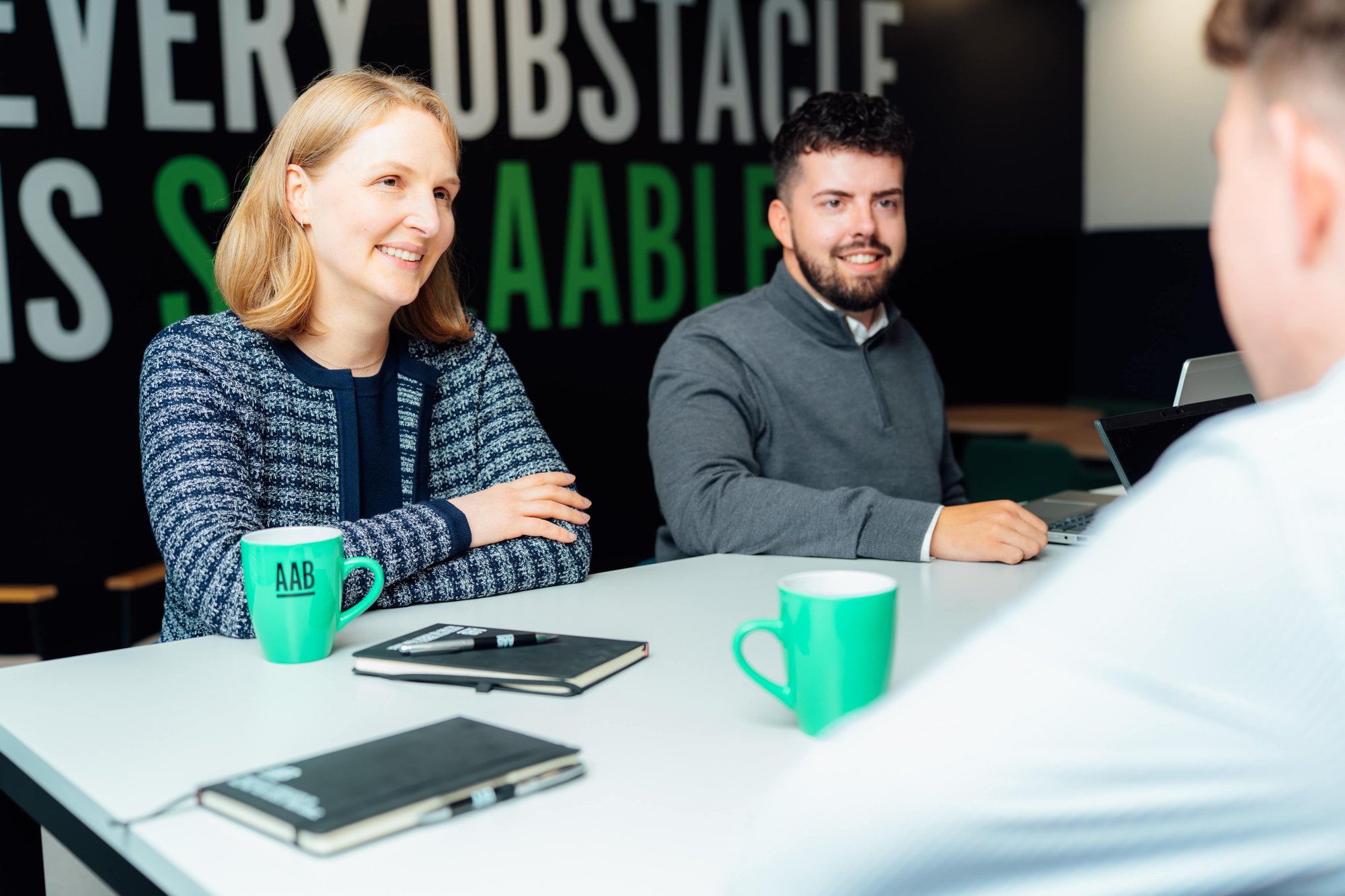 An image of two AAB employees smiling at someone across the table.