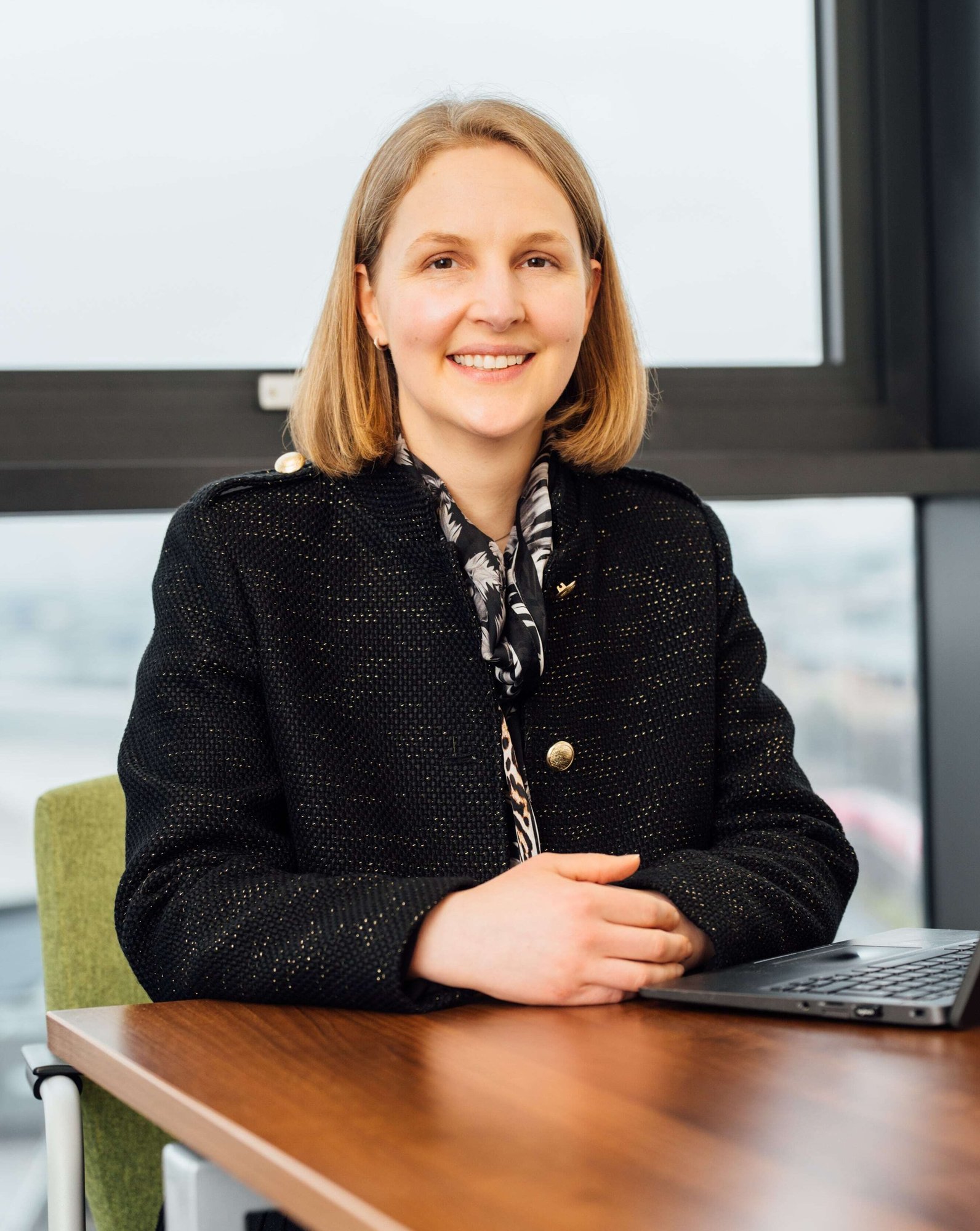 An image of Erica Fitchie wearing a black jacket and smiling at the camera.