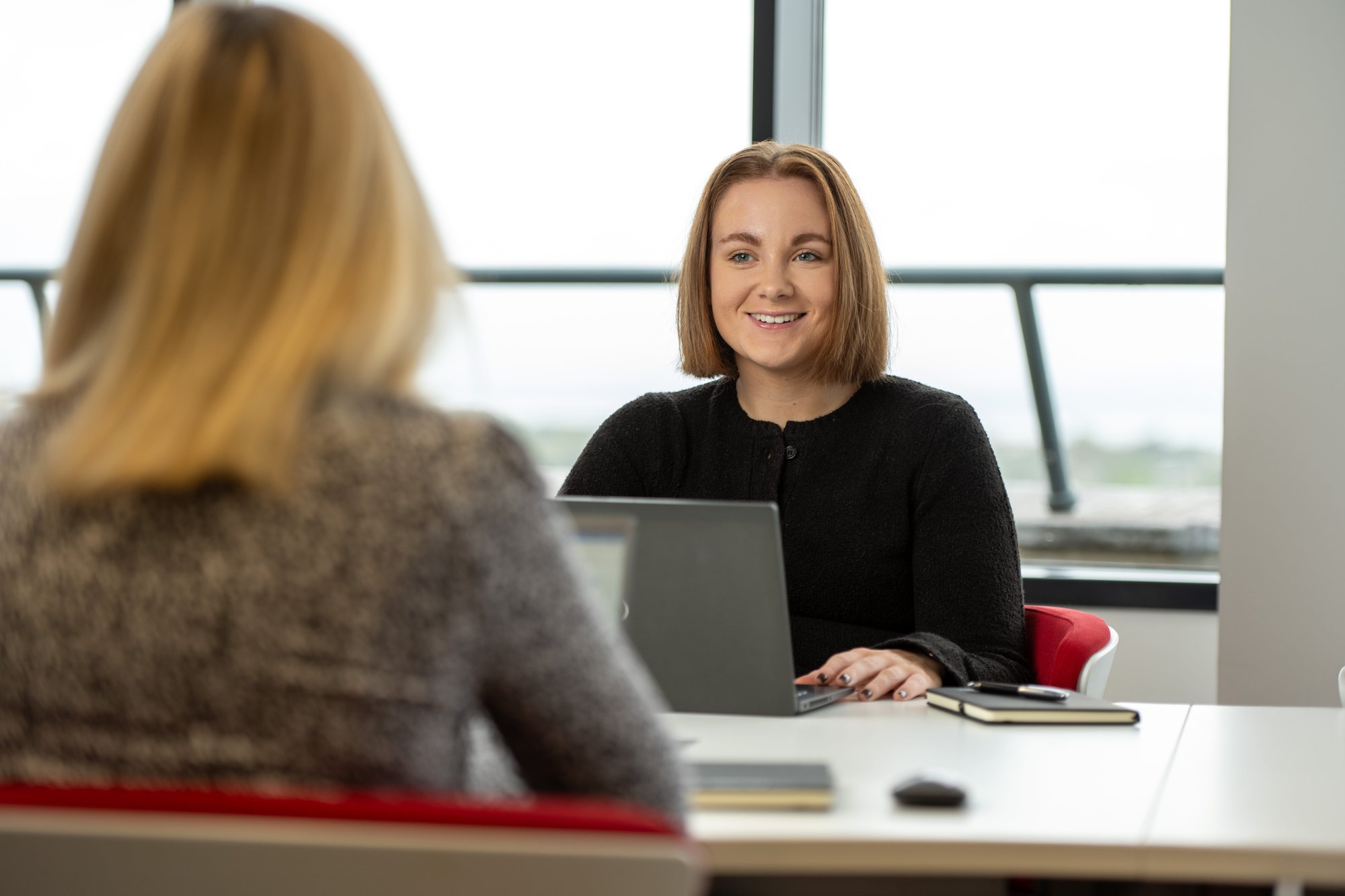 An image of Erin Rennie sitting in the Edinburgh office talking with a colleague. An image of Erin Rennie sitting in the Edinburgh office talking with a colleague.