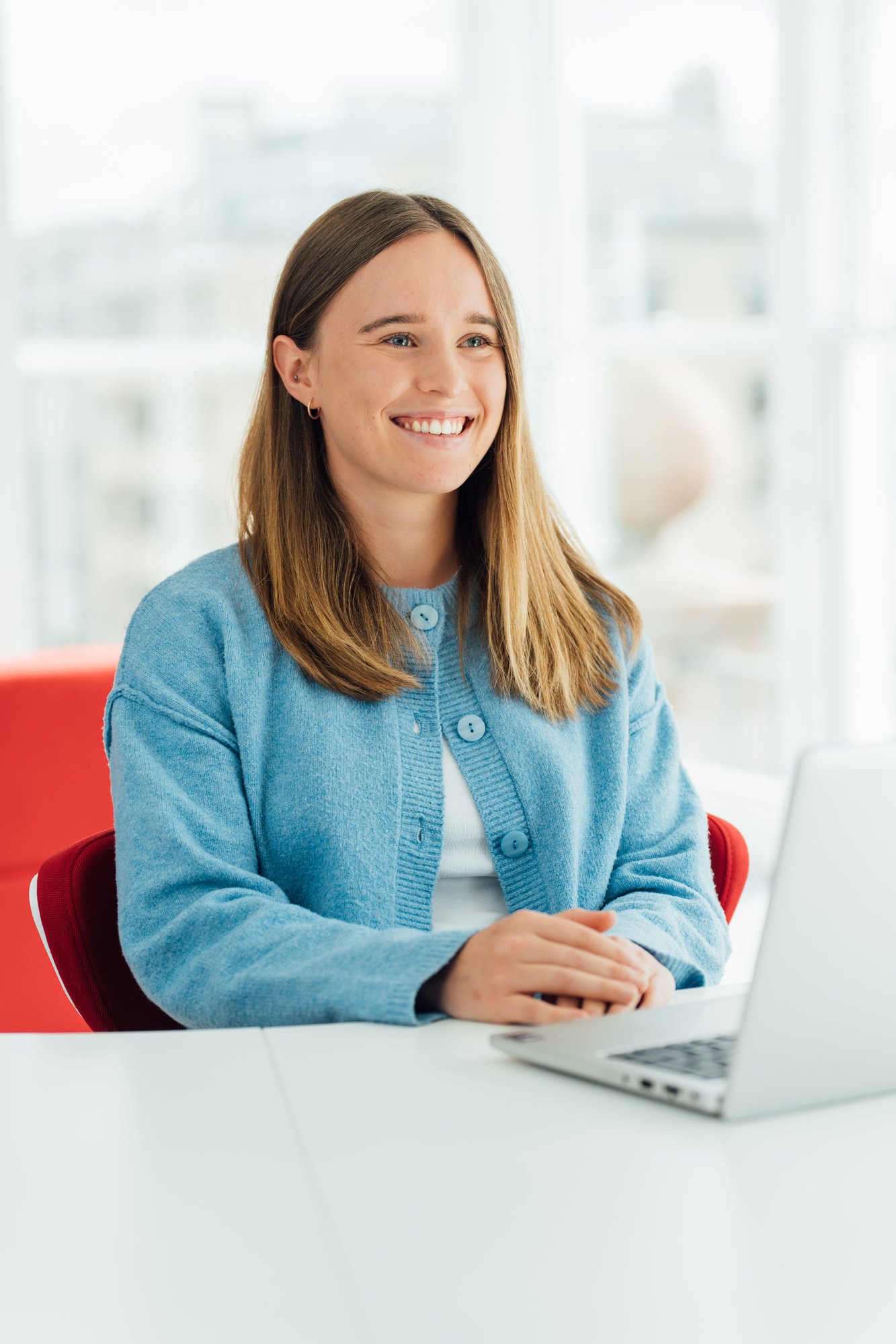 An image of Louise Neilson wearing a blue cardigan and working on her laptop.
