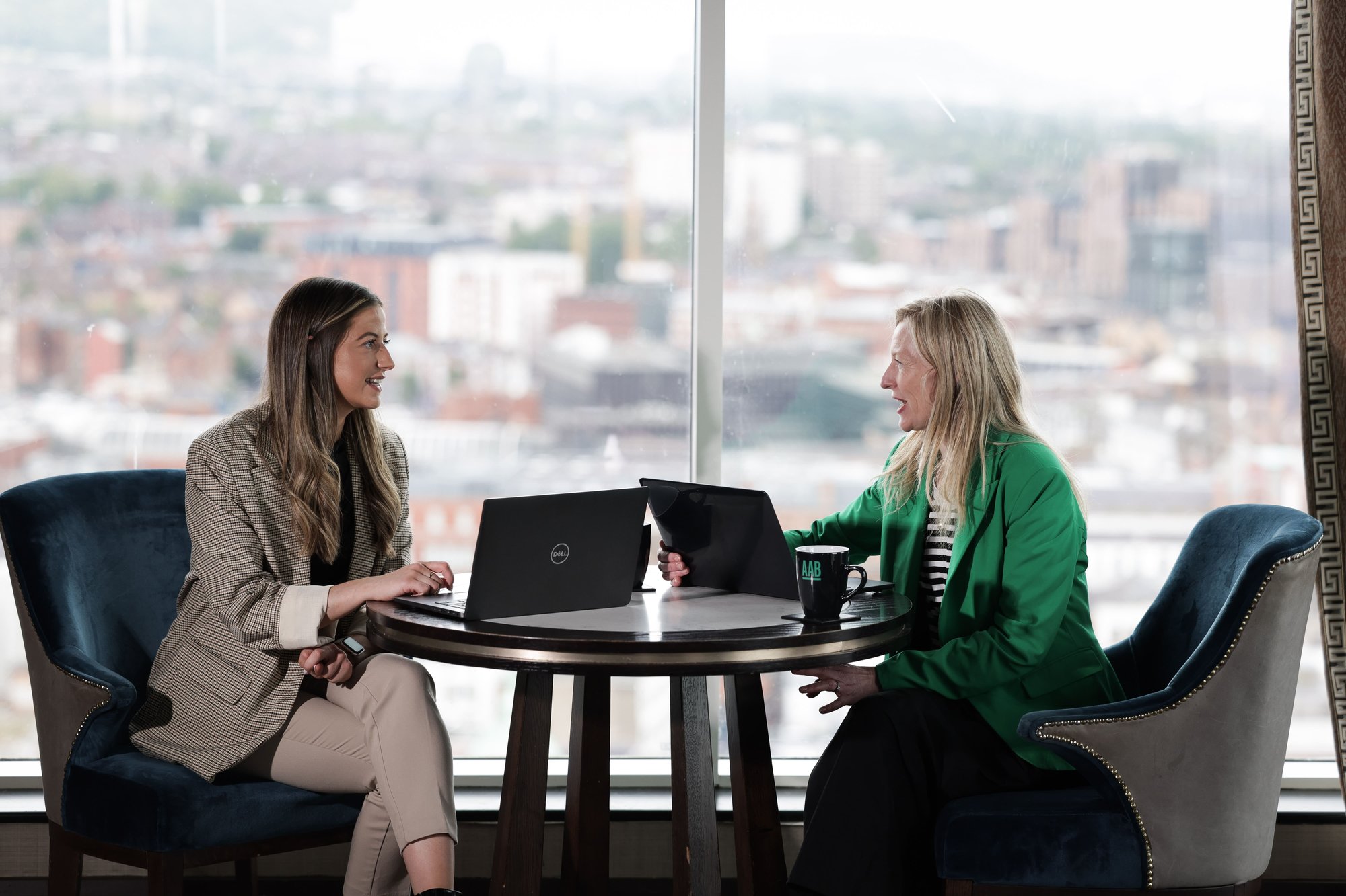 An image of two AAB employees sitting at a table with their laptops and having a conversation. An image of two AAB employees sitting at a table with their laptops and having a conversation.