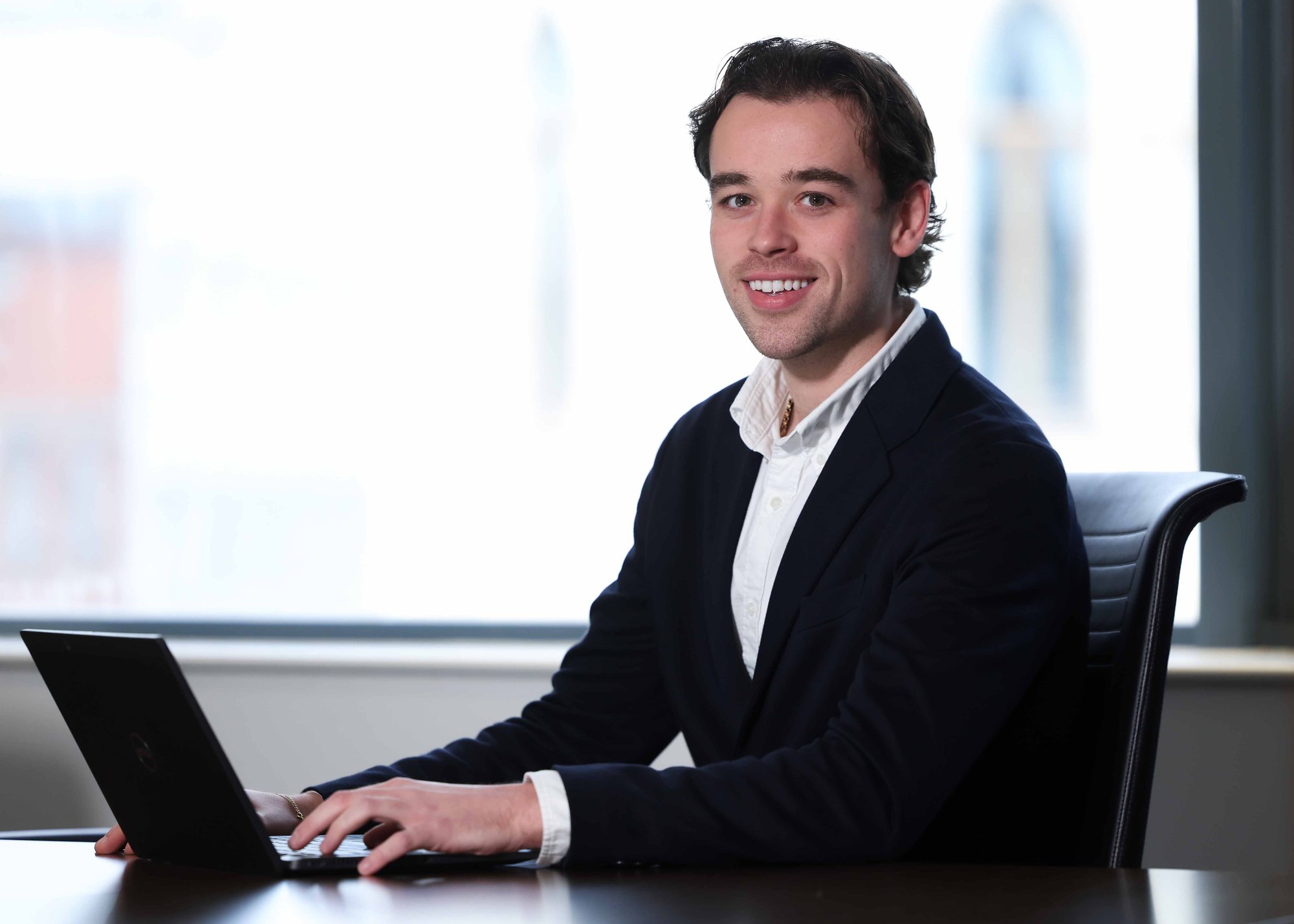 An image of Rory McCallister sitting at a desk. He is wearing a black blazer and white shirt.