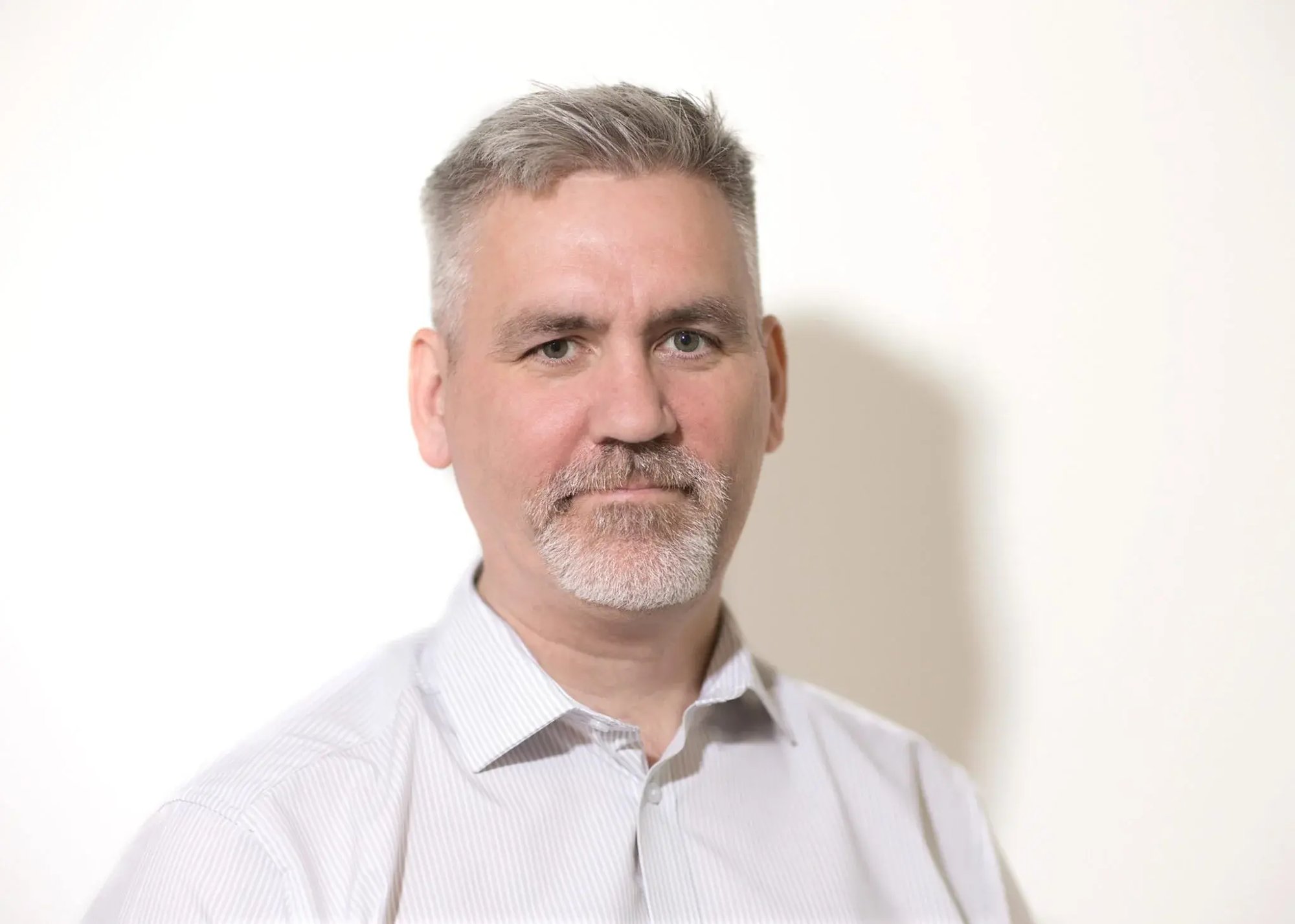 An image of Sean McAuley wearing a white shirt and looking at the camera.