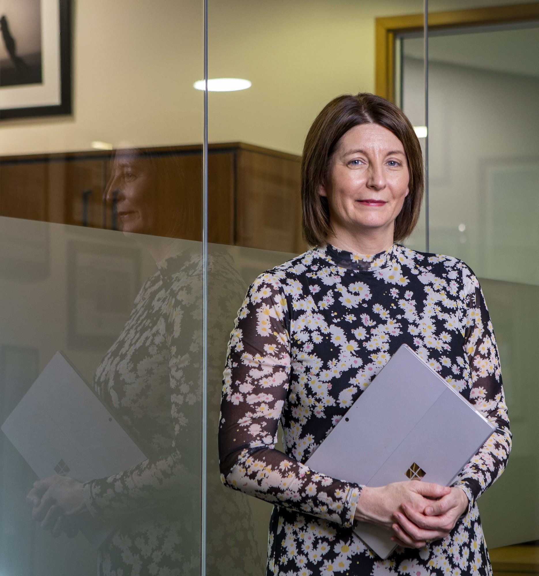 An image of Teresa Campbell holding a laptop and smiling at the camera.